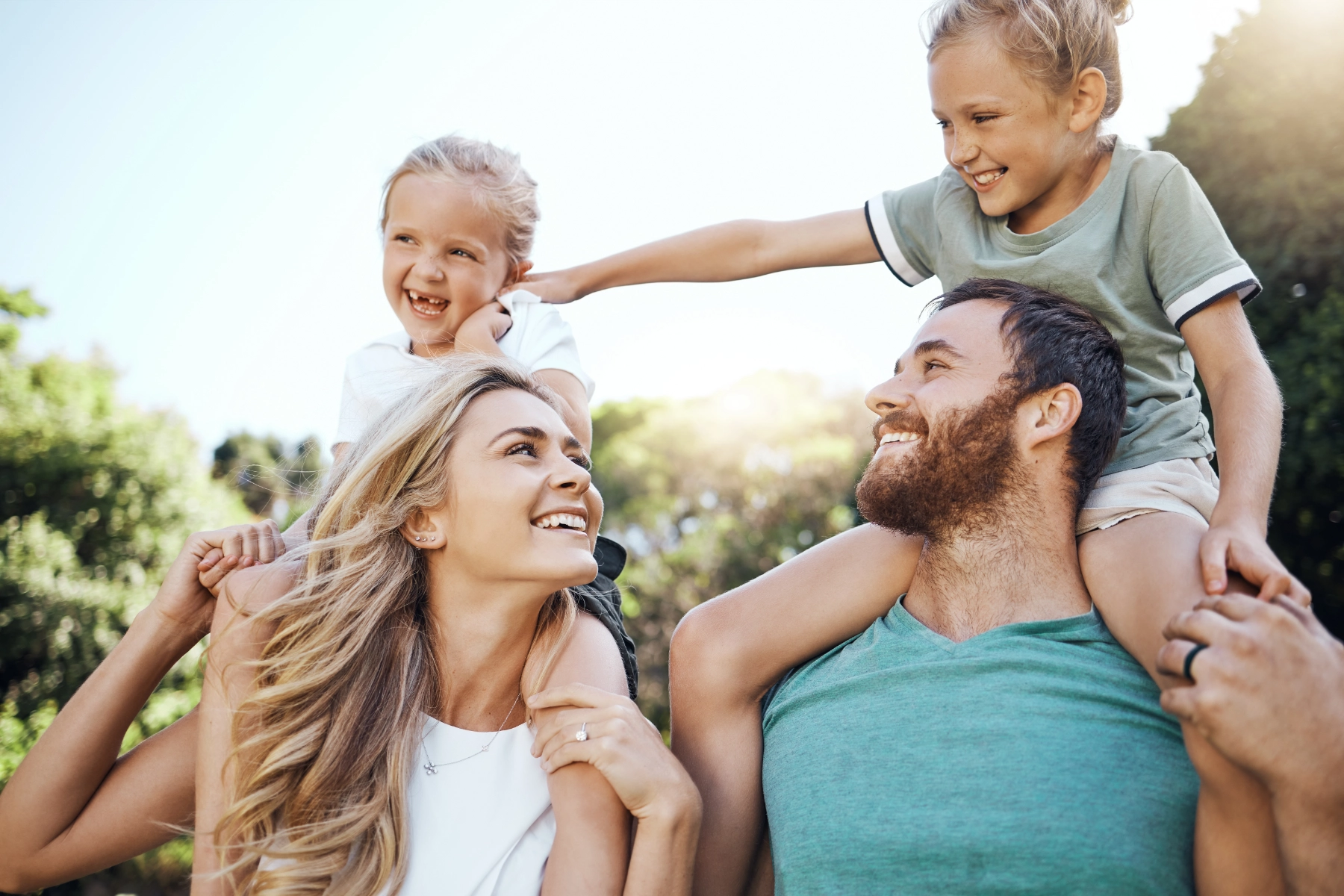 Family gathering together outdoors, kids on shoulders